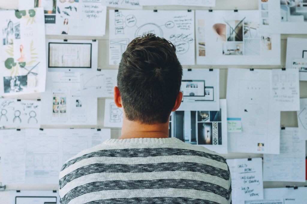 pexels-photo-212286-212286-1 A man stands in front of a wall filled with creative ideas and plans. Ideal for innovation themes.