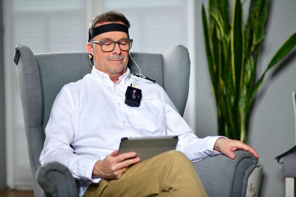 pexels-photo-24346263-24346263 Man sitting in an armchair using a neurofeedback device, illustrating modern technology in healthcare.